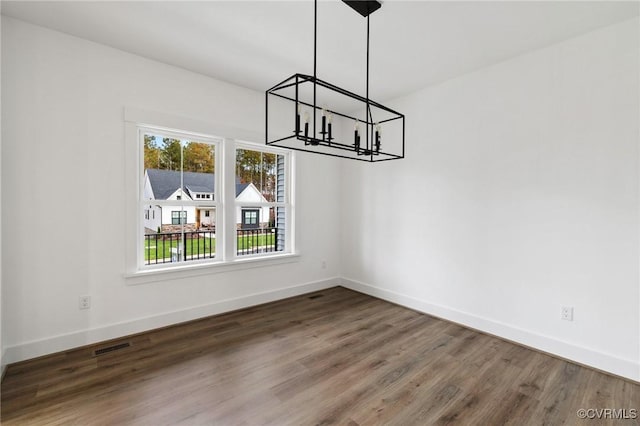 unfurnished dining area with dark hardwood / wood-style flooring and a notable chandelier