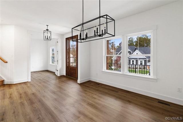 unfurnished dining area featuring hardwood / wood-style floors, a notable chandelier, and a healthy amount of sunlight