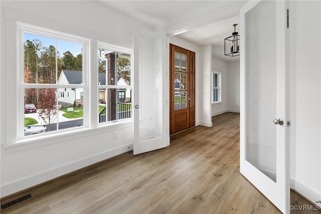 doorway to outside featuring french doors, an inviting chandelier, and light hardwood / wood-style floors