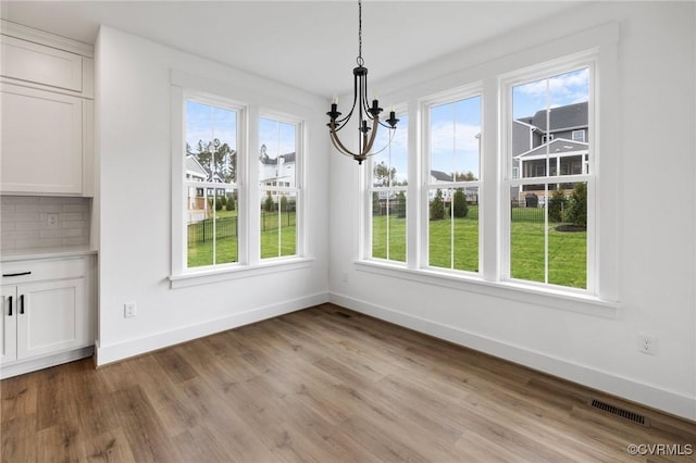 unfurnished dining area featuring light hardwood / wood-style flooring and an inviting chandelier