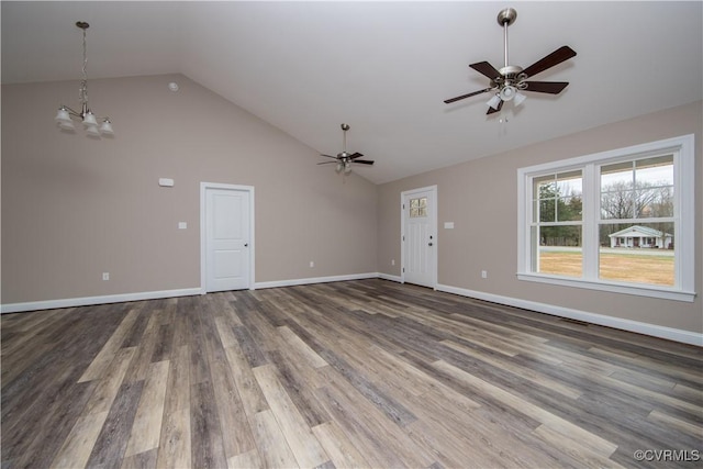 unfurnished living room featuring vaulted ceiling, dark wood-type flooring, and ceiling fan with notable chandelier