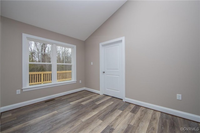 empty room featuring vaulted ceiling and hardwood / wood-style flooring