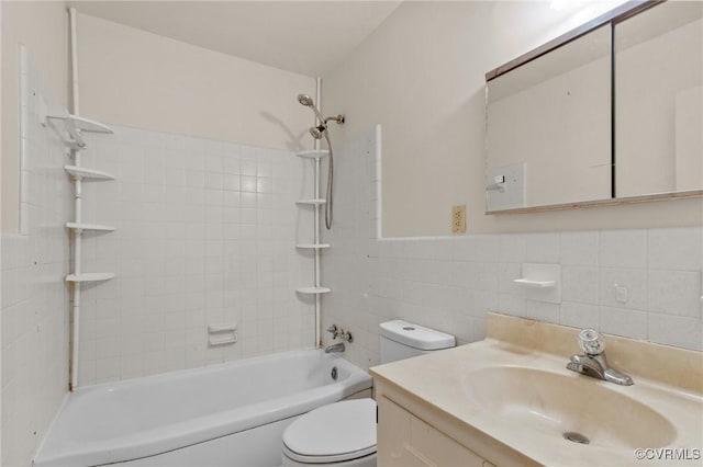 full bathroom featuring tile walls, tiled shower / bath combo, vanity, and toilet