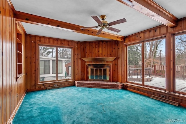 unfurnished living room with a brick fireplace, plenty of natural light, ceiling fan, and carpet flooring