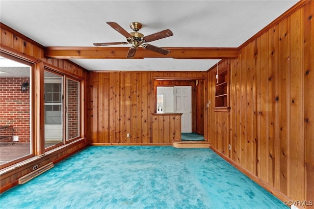 empty room with ceiling fan, beam ceiling, and carpet flooring