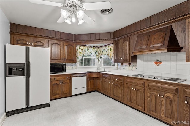 kitchen with ceiling fan, backsplash, premium range hood, sink, and white appliances