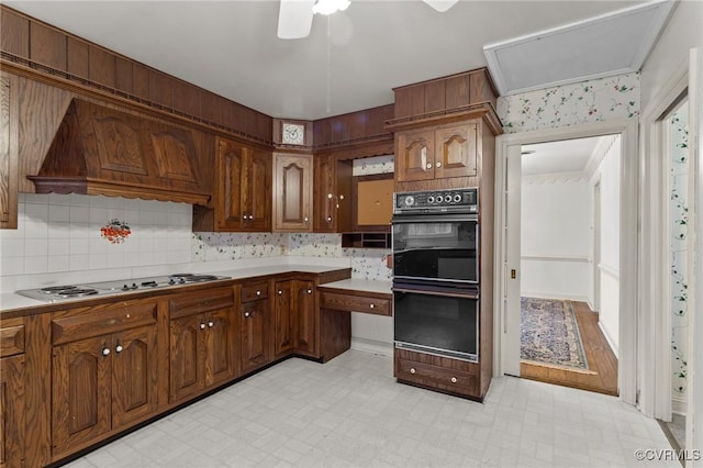 kitchen featuring black double oven, gas stovetop, ceiling fan, and custom exhaust hood