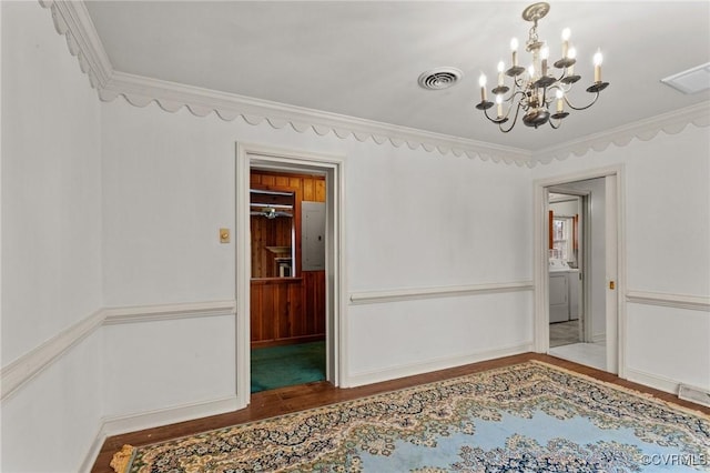 spare room featuring hardwood / wood-style floors, ornamental molding, and an inviting chandelier