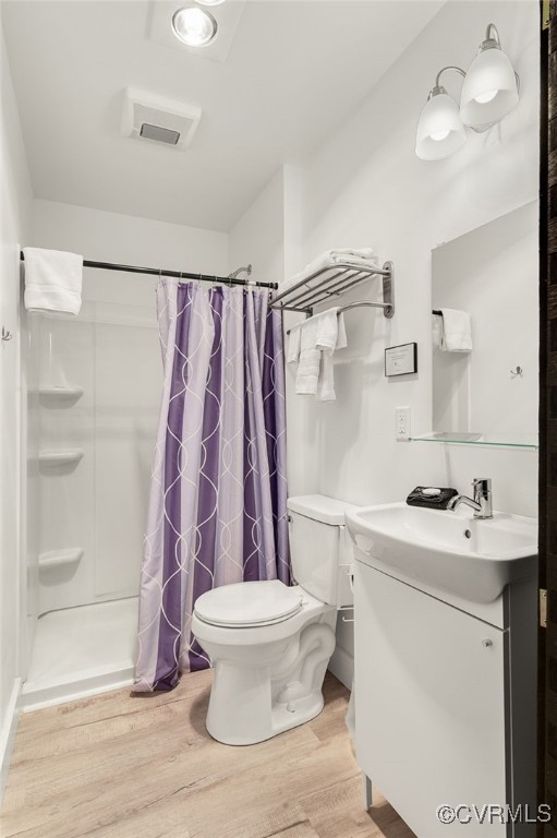 bathroom featuring toilet, hardwood / wood-style floors, walk in shower, and vanity