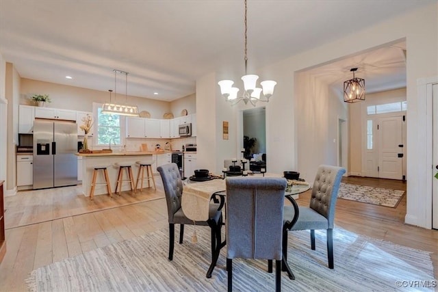 dining space with an inviting chandelier and light hardwood / wood-style floors