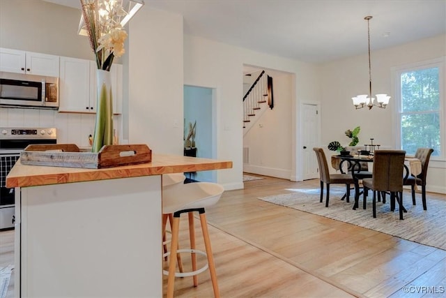 kitchen with white cabinetry, appliances with stainless steel finishes, decorative light fixtures, a chandelier, and a center island