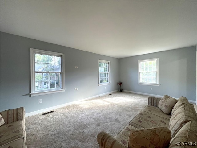 unfurnished living room featuring light carpet and a wealth of natural light