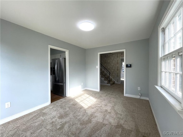 unfurnished bedroom with stainless steel refrigerator with ice dispenser, a closet, dark carpet, and a spacious closet