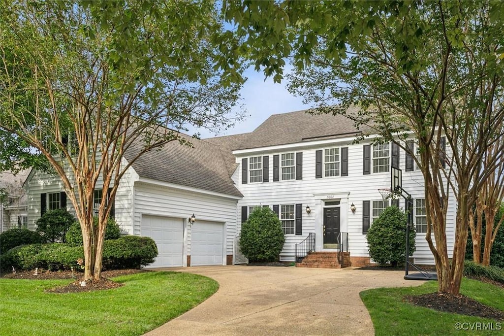 colonial-style house featuring a front yard and a garage