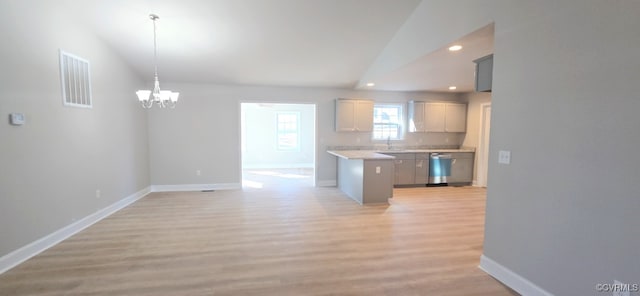 kitchen with decorative light fixtures, vaulted ceiling, dishwasher, light hardwood / wood-style flooring, and gray cabinetry