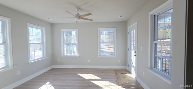 empty room featuring ceiling fan, plenty of natural light, and light wood-type flooring