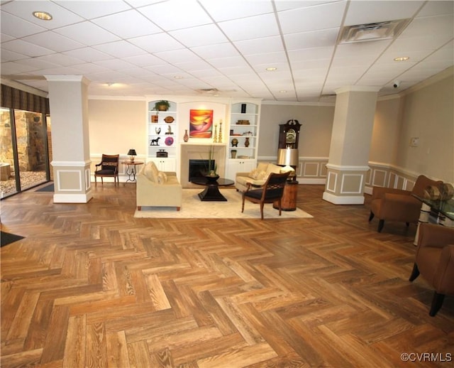 interior space featuring parquet floors, crown molding, decorative columns, and built in shelves