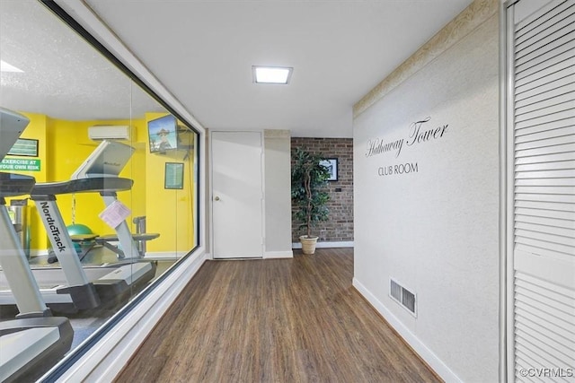 corridor featuring brick wall, dark hardwood / wood-style floors, and a wall mounted AC