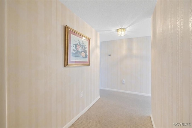 hall with light carpet and a textured ceiling