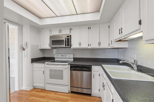 kitchen with sink, light hardwood / wood-style flooring, white cabinets, stainless steel appliances, and backsplash