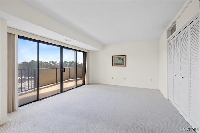 unfurnished bedroom with access to outside, light colored carpet, and a closet