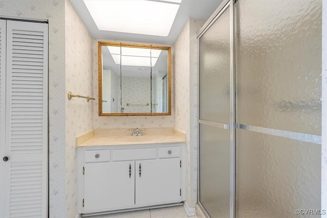 bathroom featuring a shower with door, vanity, tile patterned floors, and a skylight