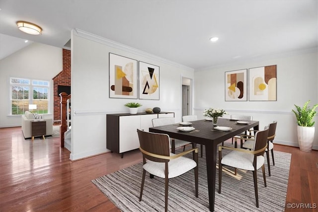 dining room featuring vaulted ceiling, ornamental molding, and wood-type flooring