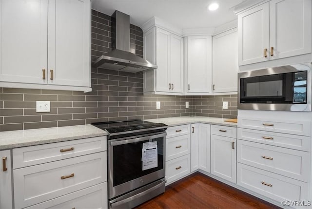 kitchen featuring built in microwave, wall chimney exhaust hood, white cabinetry, and stainless steel range with electric stovetop