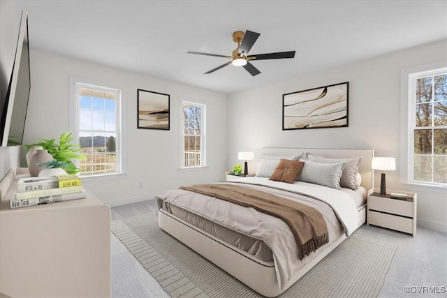 bedroom with ceiling fan, multiple windows, and light carpet