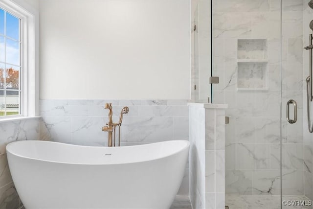 bathroom featuring separate shower and tub, tile walls, and plenty of natural light