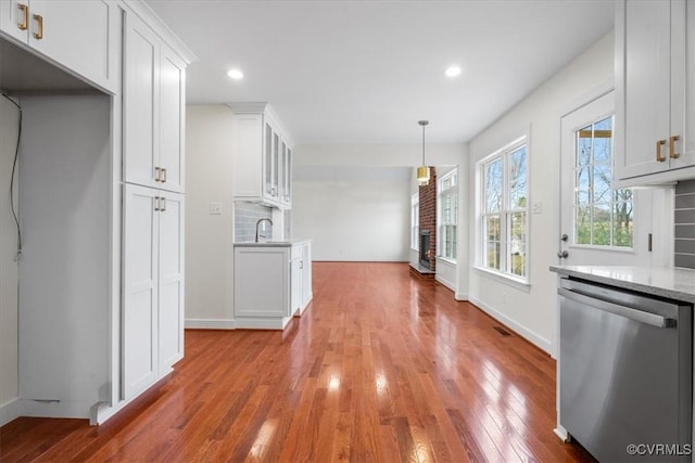 kitchen featuring pendant lighting, white cabinets, dishwasher, tasteful backsplash, and sink