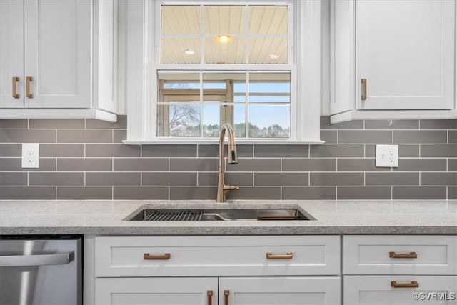 kitchen featuring backsplash, dishwasher, sink, white cabinetry, and light stone countertops