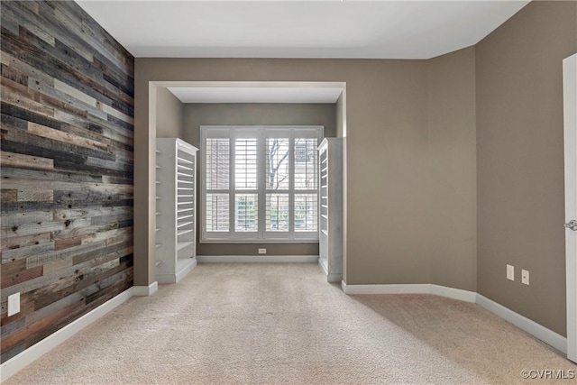 carpeted empty room featuring wood walls