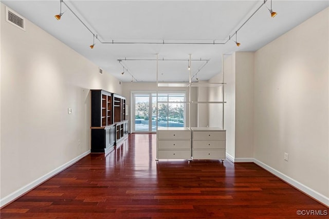 spare room with dark wood-type flooring and rail lighting