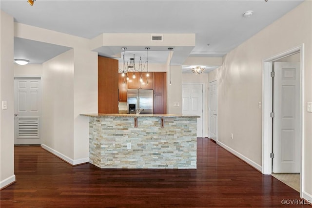 kitchen with stainless steel refrigerator with ice dispenser, dark hardwood / wood-style floors, kitchen peninsula, and decorative light fixtures