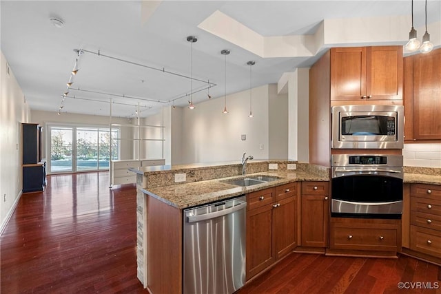 kitchen featuring decorative light fixtures, stainless steel appliances, sink, rail lighting, and light stone counters