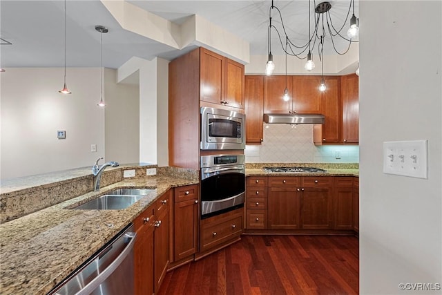 kitchen featuring stainless steel appliances, tasteful backsplash, hanging light fixtures, light stone countertops, and sink