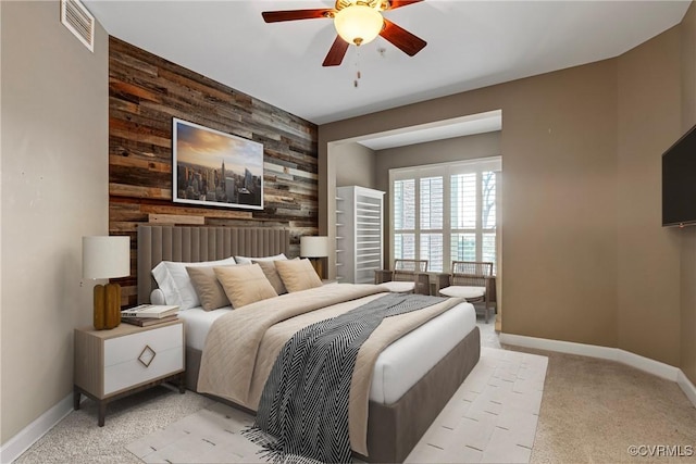 carpeted bedroom featuring ceiling fan and wood walls