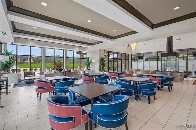 tiled dining area featuring ornamental molding and a raised ceiling