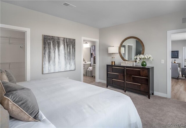 carpeted bedroom with a closet, a walk in closet, and connected bathroom