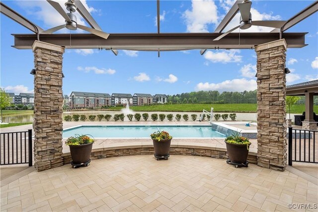 view of pool featuring ceiling fan, a water view, and a patio