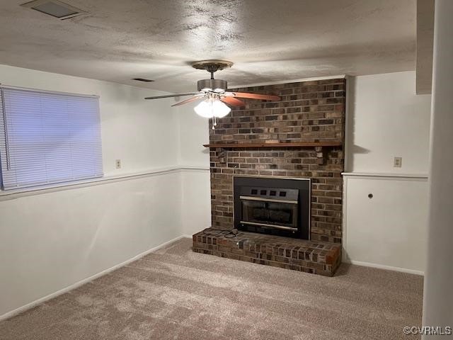 unfurnished living room featuring a brick fireplace, a textured ceiling, ceiling fan, and carpet flooring