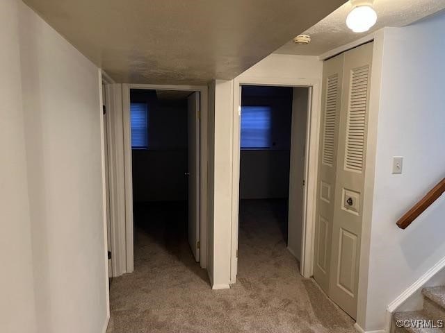 corridor featuring light carpet and a textured ceiling