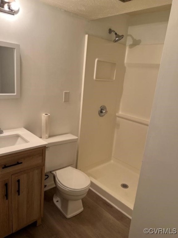 bathroom featuring hardwood / wood-style floors, a textured ceiling, vanity, toilet, and walk in shower