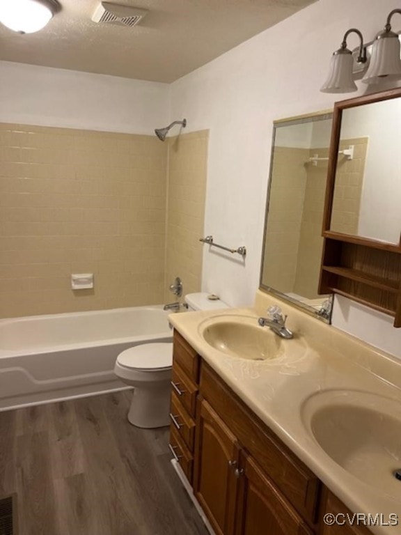 full bathroom with hardwood / wood-style floors, tiled shower / bath combo, vanity, and toilet