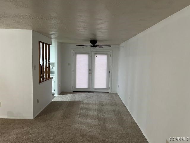 spare room with a textured ceiling, ceiling fan, carpet floors, and french doors