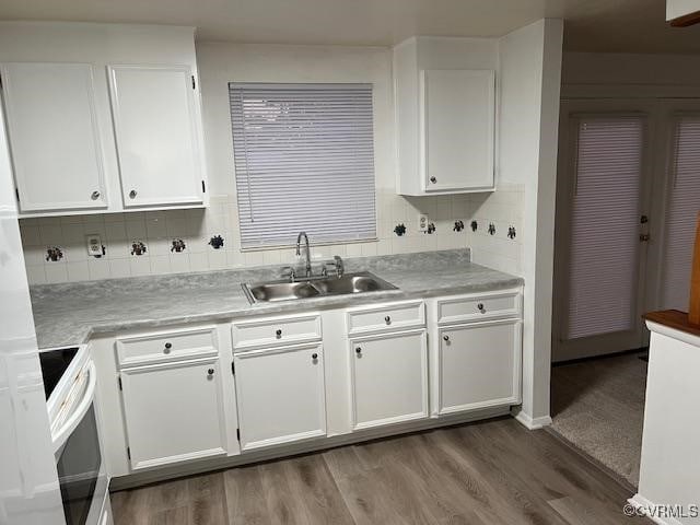 kitchen with white cabinetry, hardwood / wood-style flooring, decorative backsplash, white range with electric cooktop, and sink