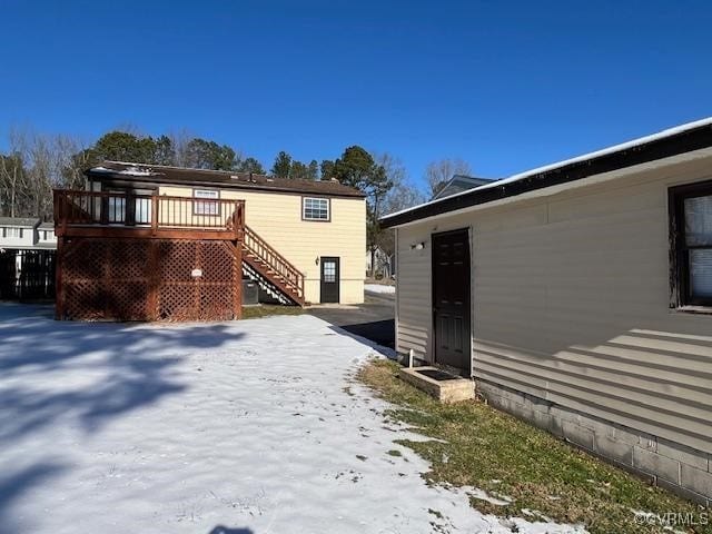 snow covered back of property featuring a deck