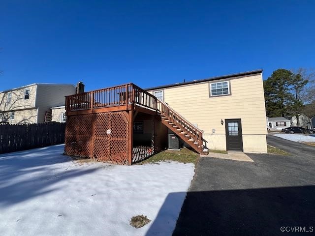 snow covered rear of property with a wooden deck