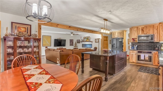 kitchen featuring appliances with stainless steel finishes, pendant lighting, a textured ceiling, and dark hardwood / wood-style flooring